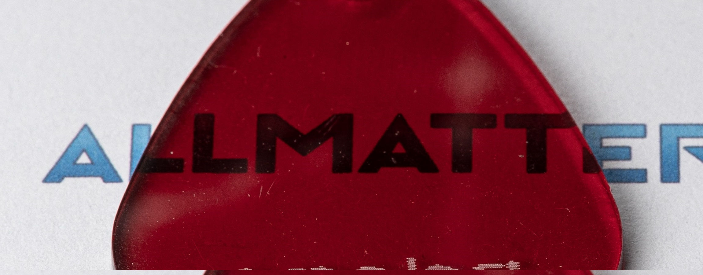 Czerwony element z logo ALLMATTER na jasnym tle